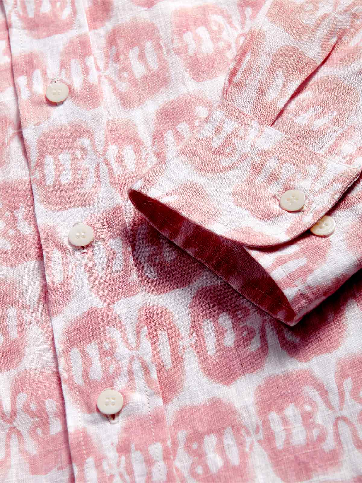 Close-up of a pink and white linen long sleeve shirt with button details, featuring a block-printed design of mirrored Asian elephants.