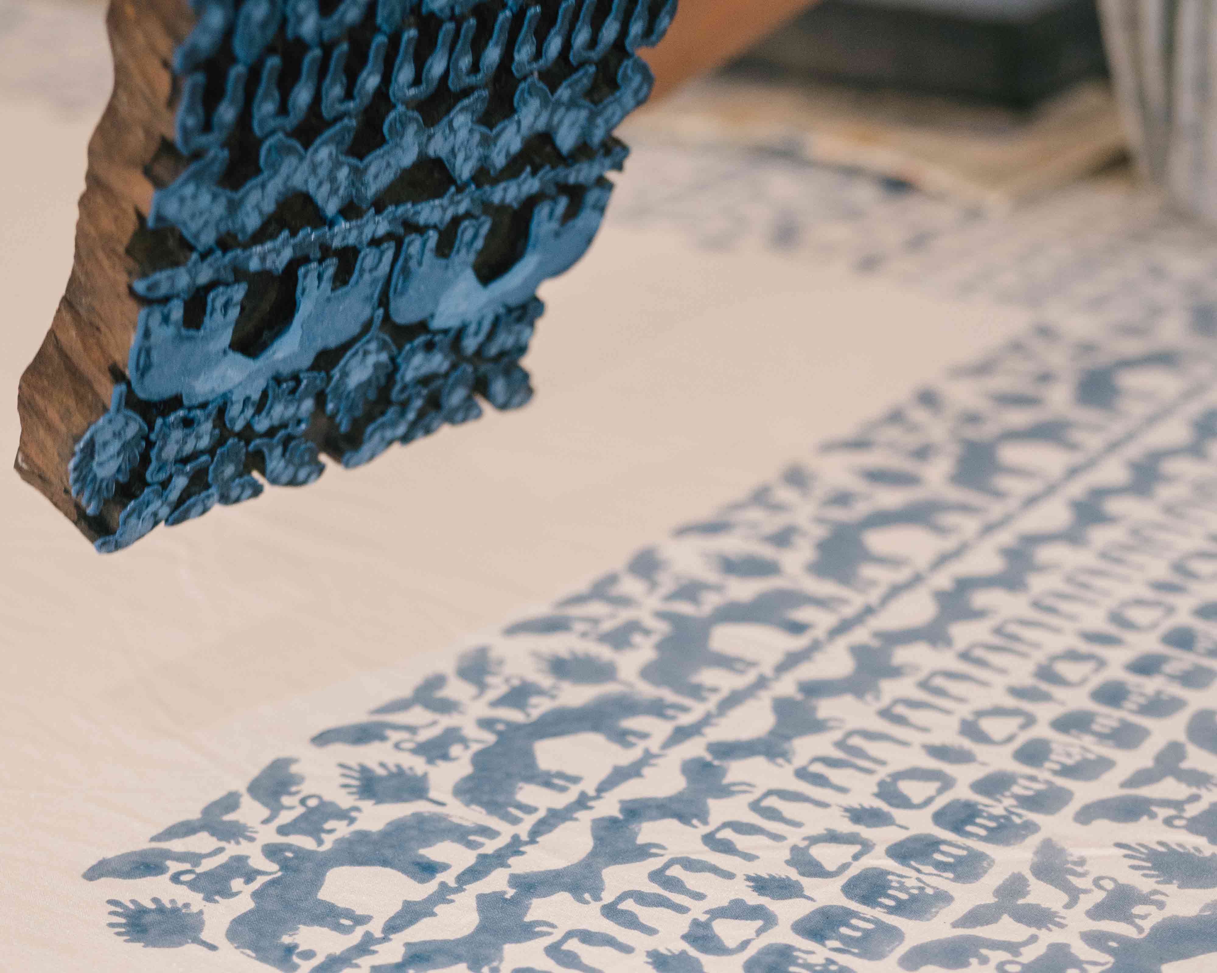 Wooden block printing block dipped in blue dye creating Love Brand & co. coexist pattern.