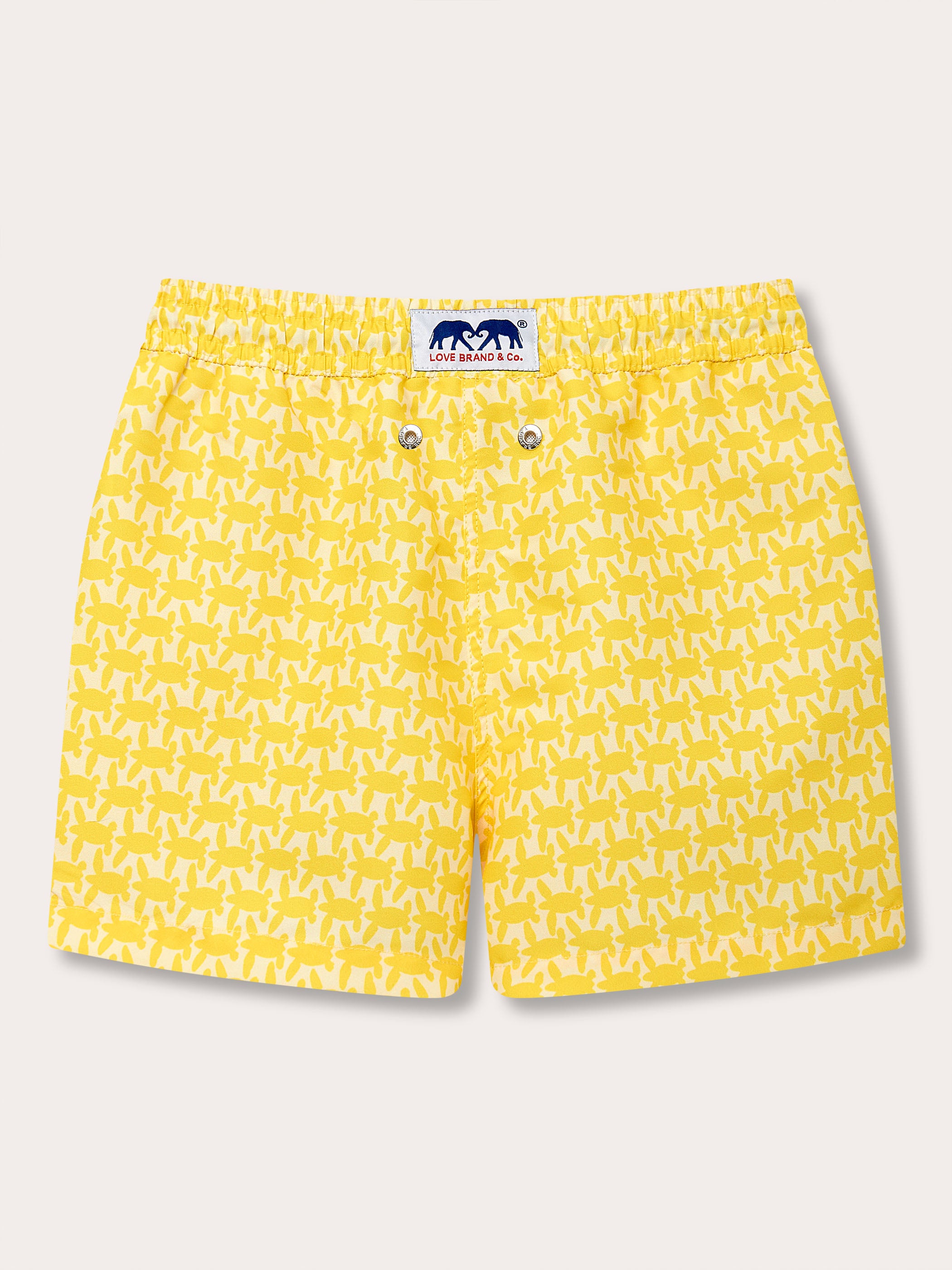 Yellow boys' swim shorts with a turtle print design inspired by SJ Villas' Caribbean properties, emphasizing turtle conservation.