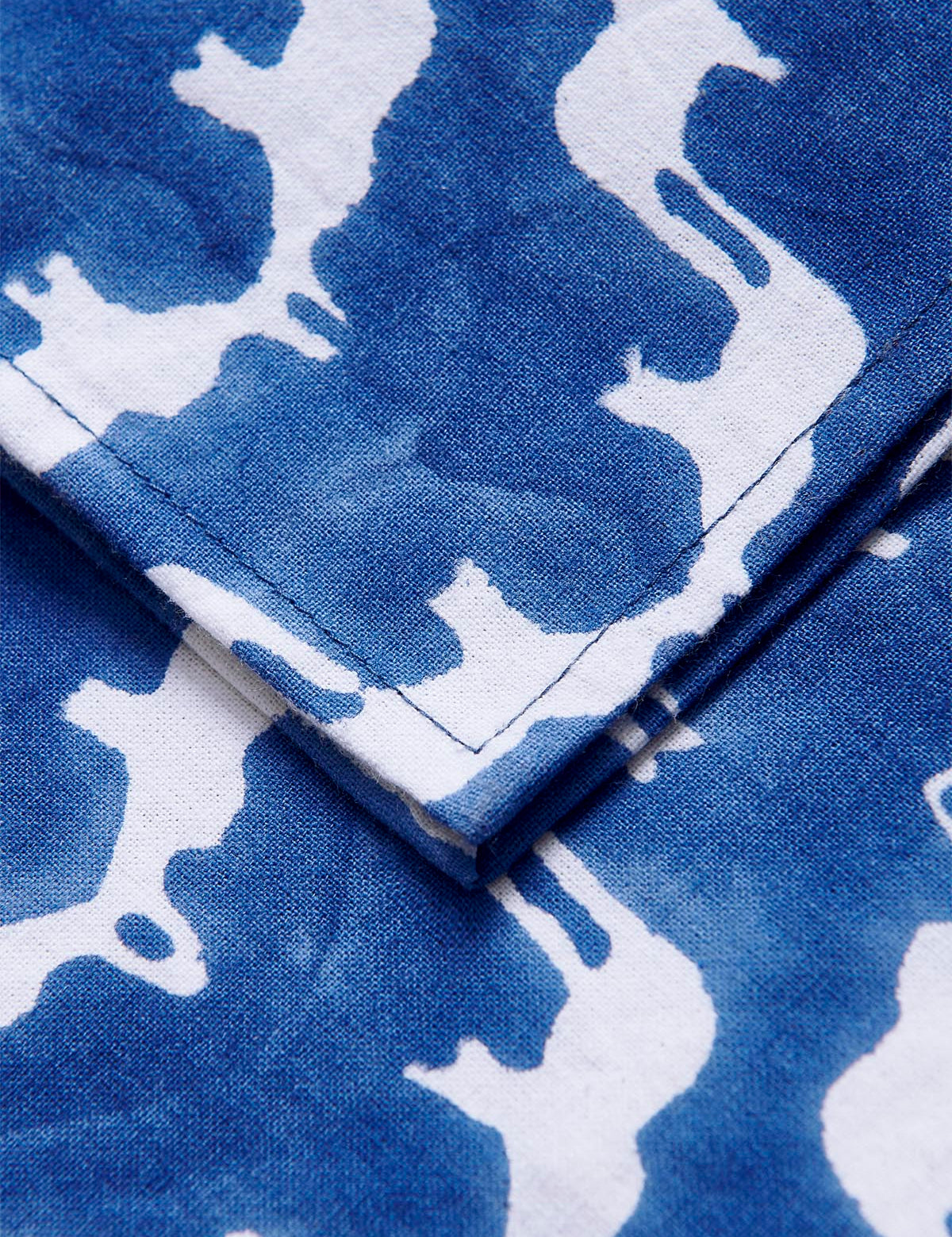 Set of four blue cotton napkins featuring an intricate white block-print design of Asian elephants, crafted by artisans in India.