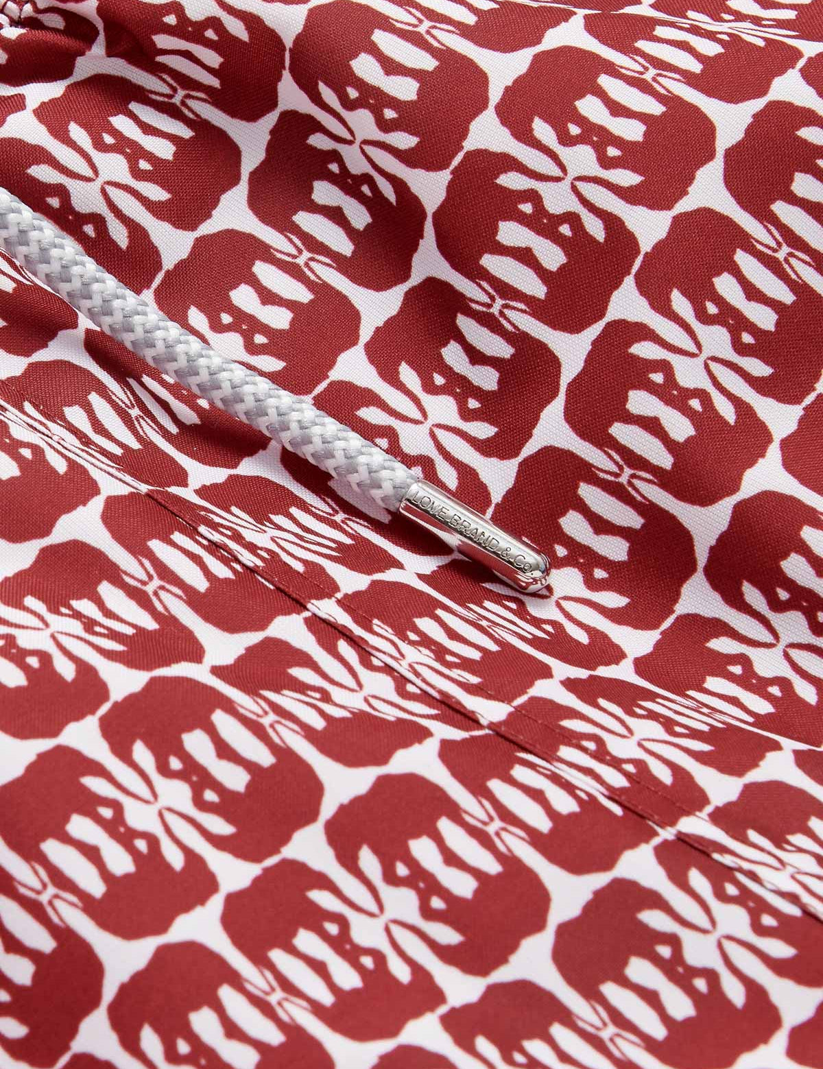 Close-up view of Men's Elephants of India Staniel Swim Shorts showing dark burgundy elephant pattern on a crisp white background with a white drawstring.