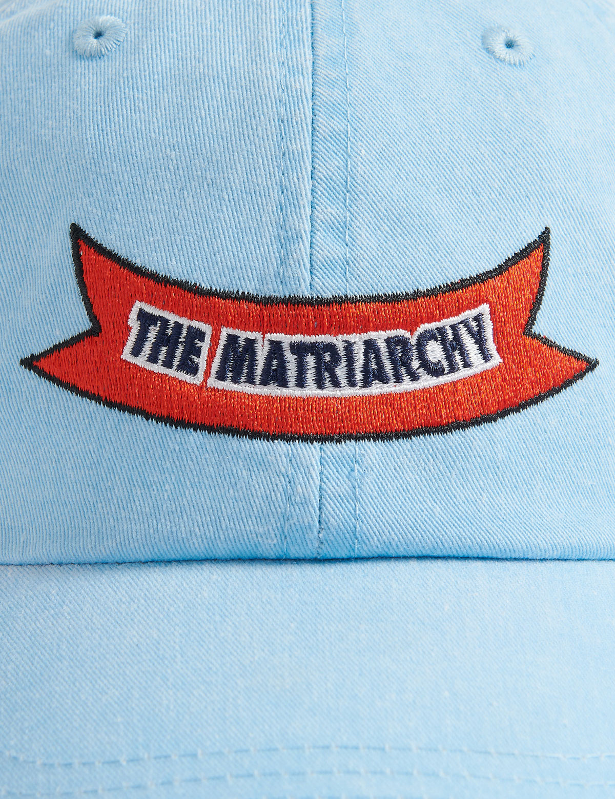 Sky blue cotton peak cap featuring 'The Matriarchy' ribbon embroidery on the front.