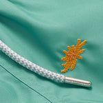 Close-up of Boys Primavera Staniel Swim Shorts in riviera green with embroidered sea flower detail and drawstring.