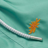 Close-up of Boys Primavera Staniel Swim Shorts in riviera green with embroidered sea flower detail and drawstring.