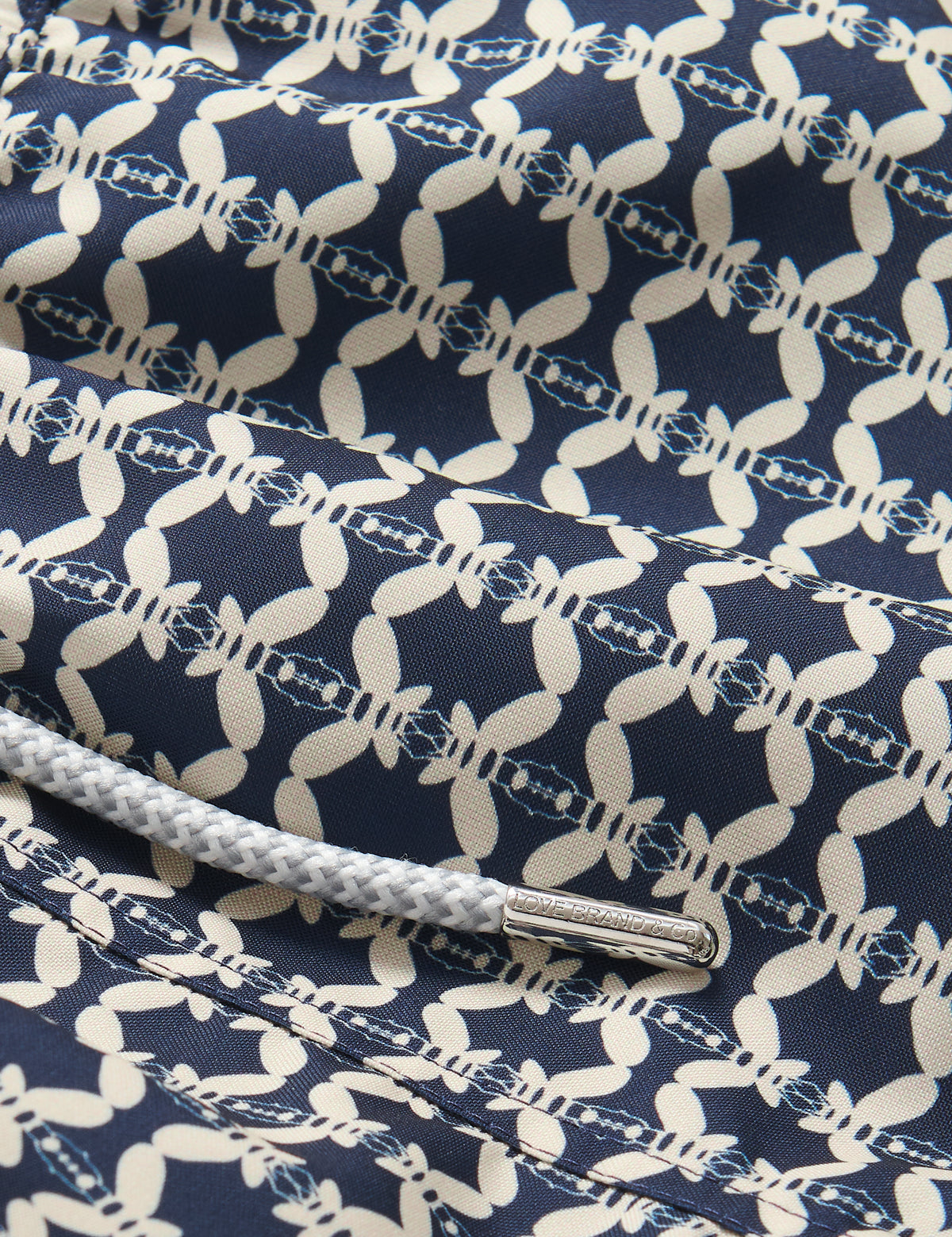 Close-up view of Boys Bee Propelled Staniel Swim Shorts featuring a unique stone-coloured bee print on a deep blue background made from 100% recycled materials.