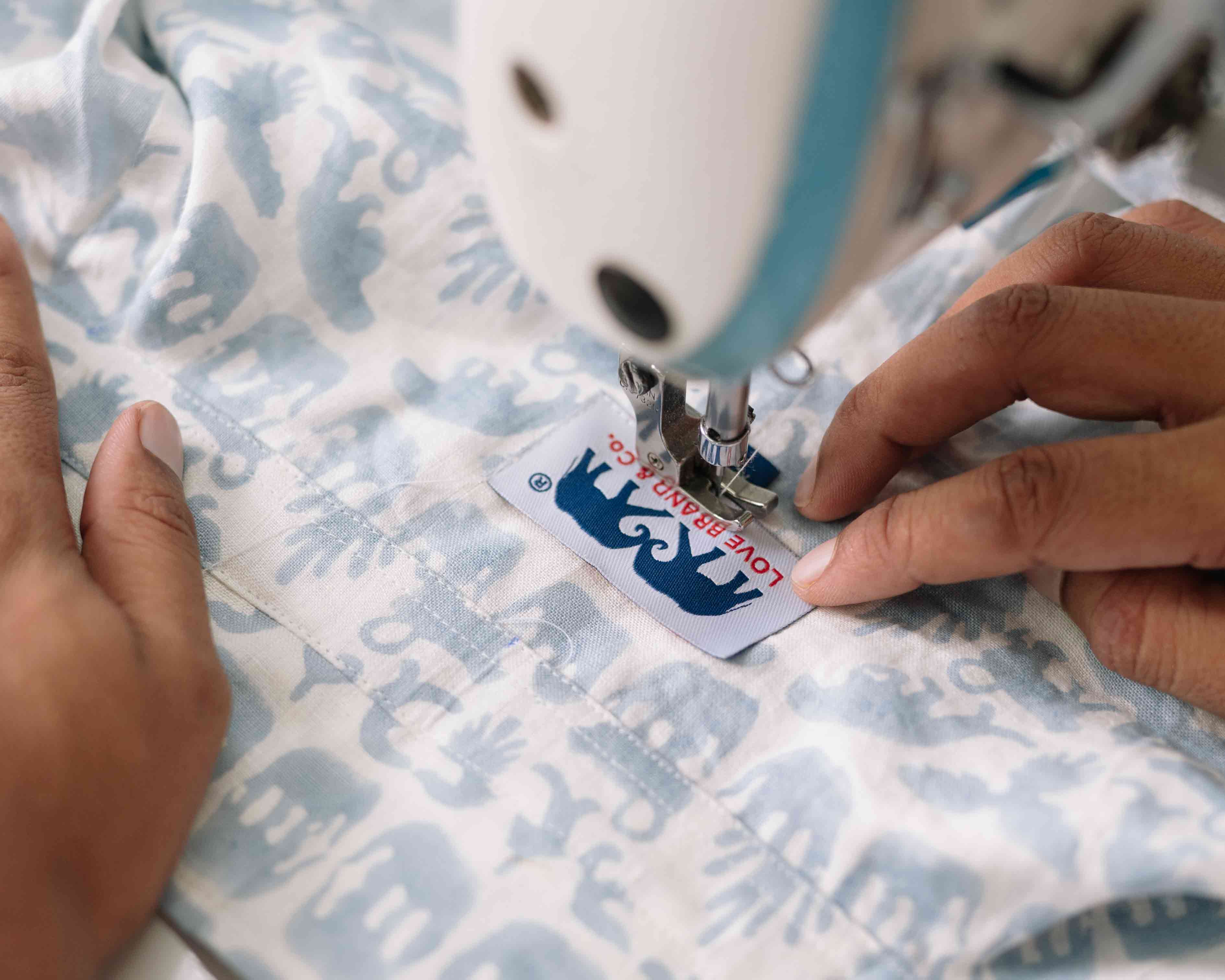 Love Brand & Co. label being sewn onto coexist men's linen sirt.