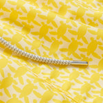 Yellow swim shorts with an all-over turtle print pattern, dedicated to raising awareness about the endangered turtles in Barbados, featuring a white drawstring cord.