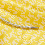 Yellow swim shorts with an all-over turtle print pattern, dedicated to raising awareness about the endangered turtles in Barbados, featuring a white drawstring cord.