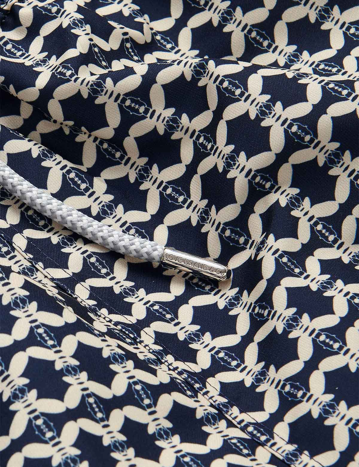 Close-up of the fabric detail on Men's Bee Propelled Staniel Swim Shorts with white bee patterns on a navy background and a grey drawstring.