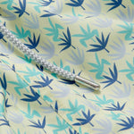 Close-up of Men's Palm Sugar Staniel Swim Shorts with lush fan palm design in pale yellow and blue accents, featuring a braided drawstring.