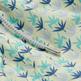 Close-up of Men's Palm Sugar Staniel Swim Shorts with lush fan palm design in pale yellow and blue accents, featuring a braided drawstring.