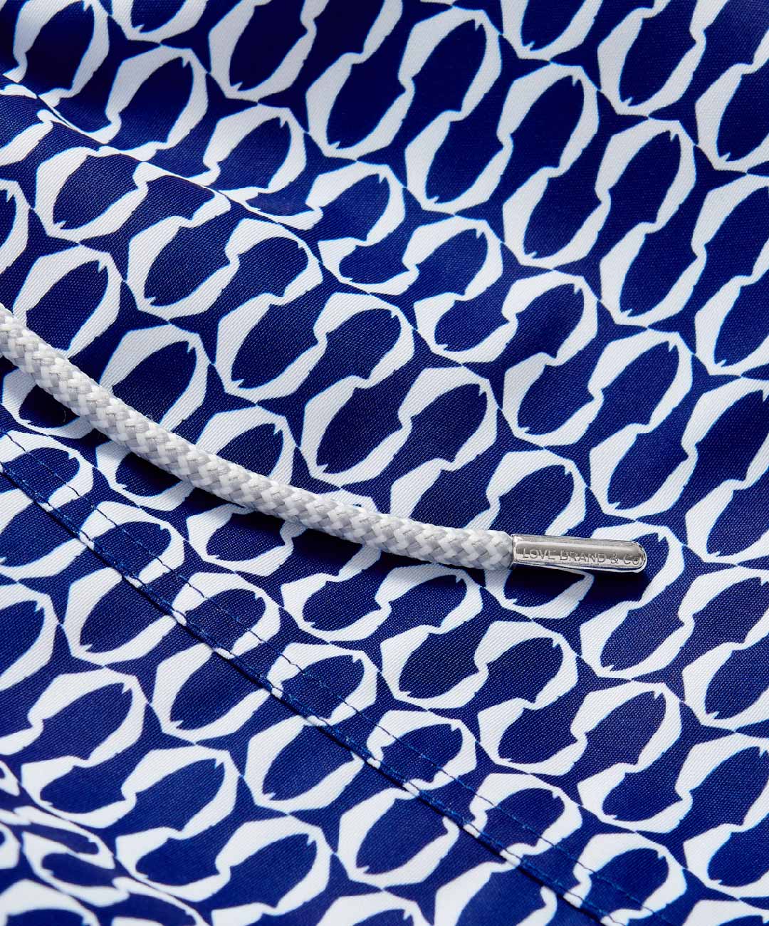 Staniel pine cay mens swim shorts. The sleek geometric pattern, representing white schools of fish swimming together on a dark blue background.