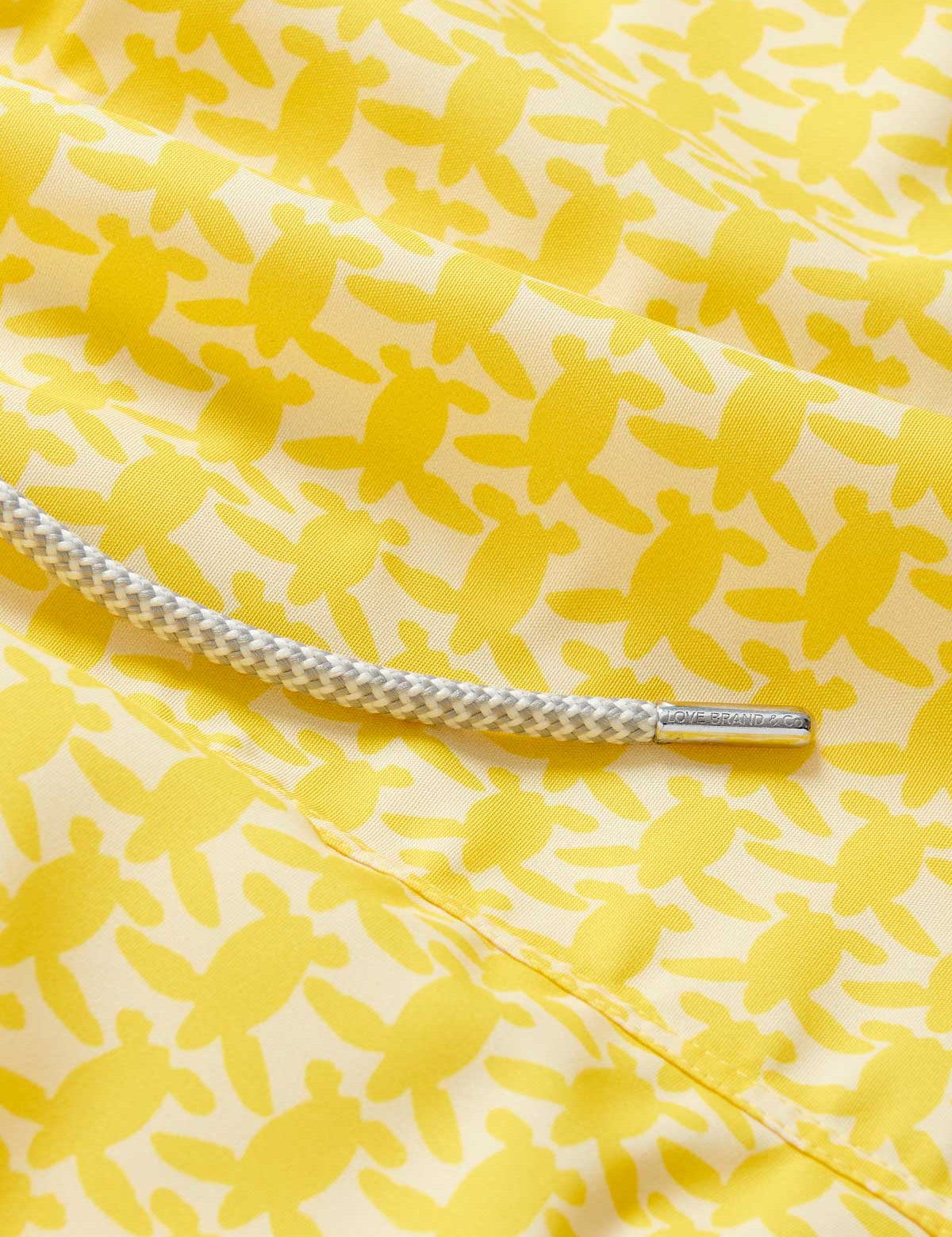 Close-up of Men's Turtle Light Staniel Swim Shorts in sunny yellow with a pattern of small turtles and a white adjustable drawstring.