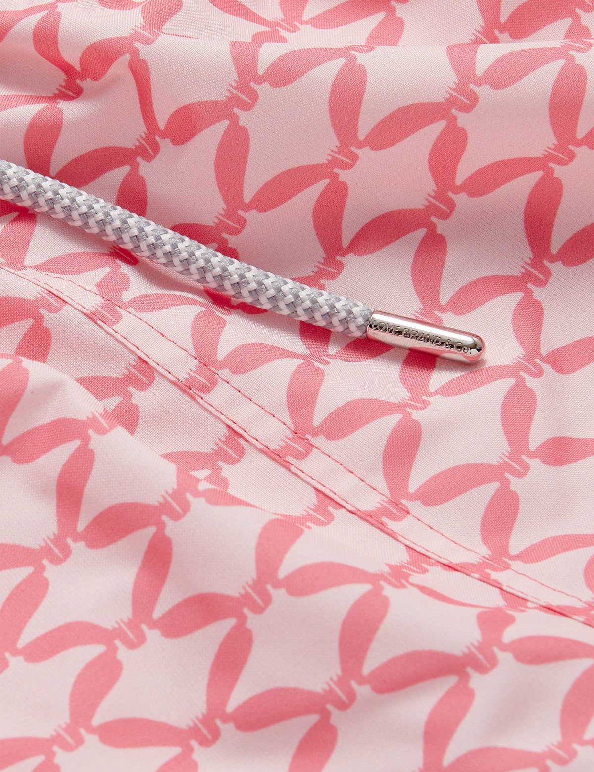 Close-up view of Men's Ray Rhythm Staniel Swim Shorts showcasing a distinct diamond geometric print. Patterned swim shorts with graceful manta rays in soothing watermelon and light pink hues, and a detailed braided drawstring.