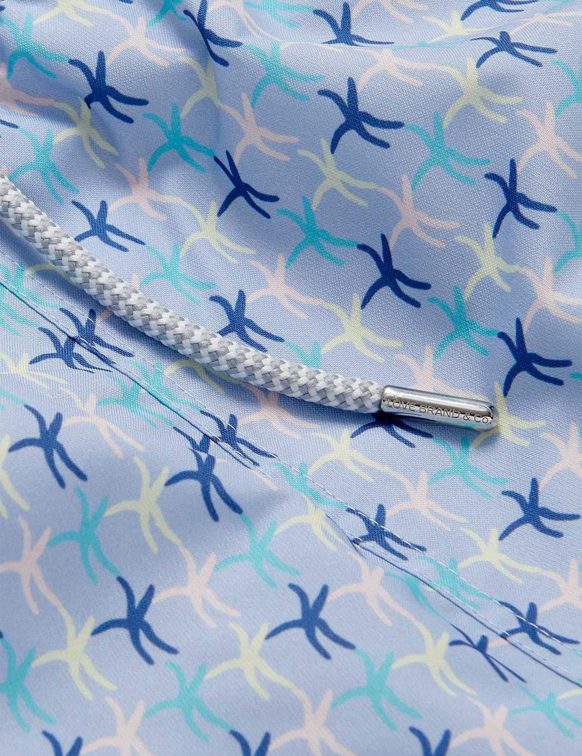 Close-up of the sea star pattern on the Men's Star Dancer Staniel Swim Shorts, showcasing pastel pink, zesty limoncello, fresh cay green, and deep ocean blue hues with a braided drawstring.